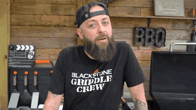 a man with a beard wears a black t-shirt that says blackstone griddle crew