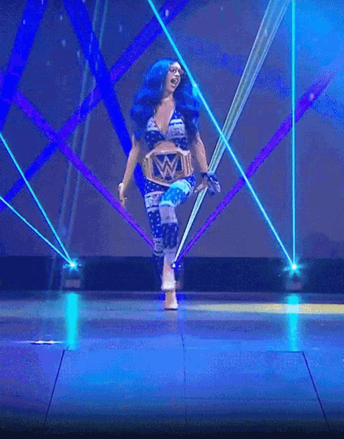 a woman in a blue wrestling outfit is holding a wwe belt