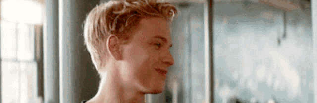 a close up of a young man 's face with blonde hair and a smile on his face .