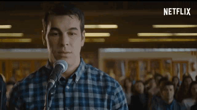 a man in a plaid shirt is singing into a microphone with a netflix logo in the corner