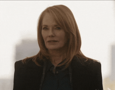 a woman with red hair is wearing a black jacket and a blue shirt .
