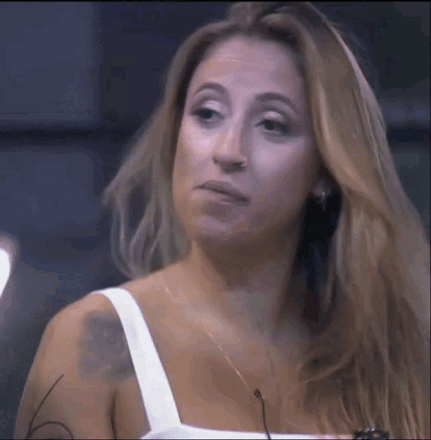 a woman with long blonde hair is wearing a white top