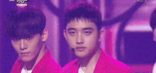 a group of young men are standing on a stage wearing pink jackets .