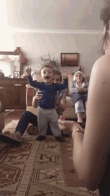 a little boy in a blue shirt is being held by a woman