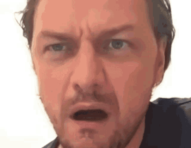 a close up of a man making a funny face with his mouth open .