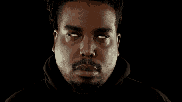 a man with dreadlocks and a beard wearing a black hoodie