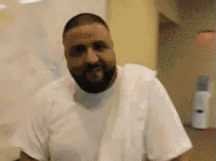 a man with a beard wearing a white shirt is standing in a room .