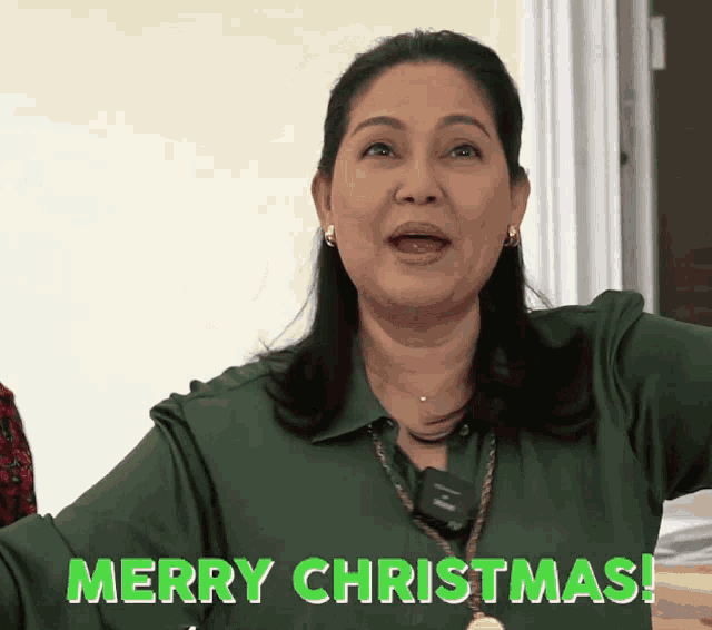 a woman in a green shirt says merry christmas in green letters