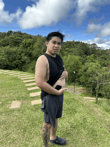 a man with a tattoo on his leg is standing in a field