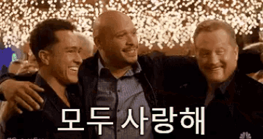 a group of three men are posing for a picture together in front of a crowd .