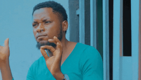 a man with a beard is wearing a blue shirt and making a funny face