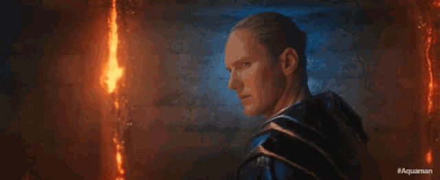 a man is standing in front of a wall with fire coming out of it .
