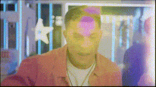 a man in a pink jacket is standing in front of a fence with a star on it .
