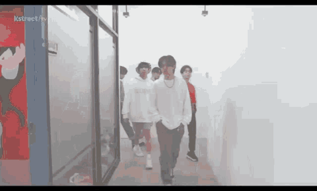 a group of young men are walking down a hallway in a room .