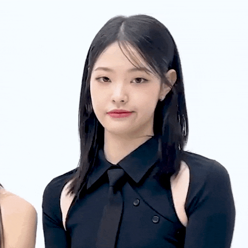 a young woman wearing a black shirt and tie is standing in front of a white background .