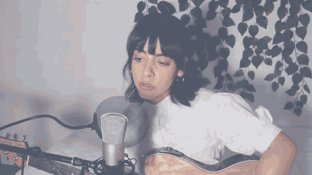 a woman is singing into a microphone while playing a guitar