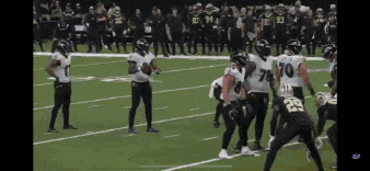 a football game is being played on a field with players standing on the sidelines .