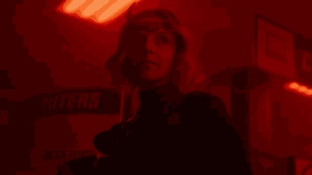 a woman talking on a cell phone in a dark room with a sign that says water
