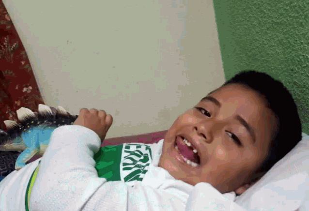 a young boy laying on a bed with a shirt that says ' ecko ' on it