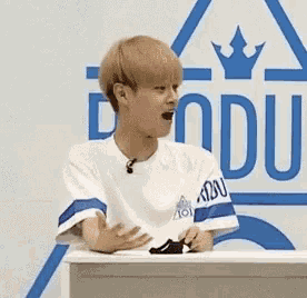 a young man is sitting at a table with his hands outstretched in front of a podium .