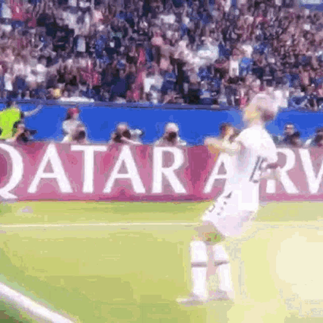 a soccer player is running on the field in front of a qatar banner