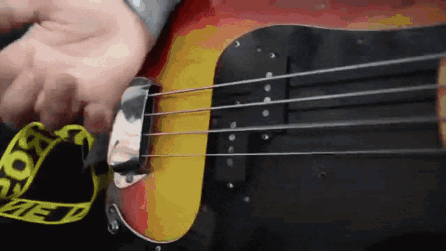 a person is playing a bass guitar with a yellow belt that says " off white " on it
