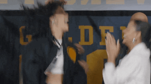 a man and a woman are giving each other a high five in front of a sign that says g.d.f.
