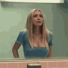 a woman is standing in front of a mirror in a bathroom .