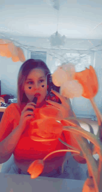 a girl is taking a picture of herself in front of flowers