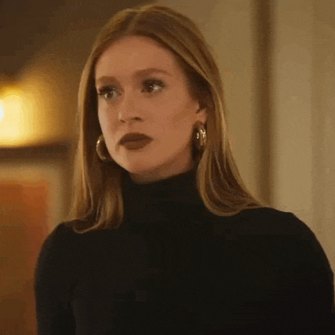a woman wearing a black turtleneck sweater and hoop earrings is looking at the camera .