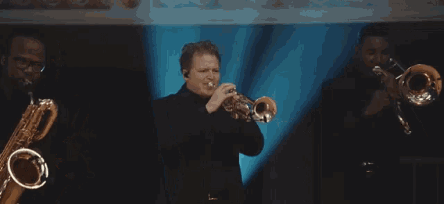 a man in a black suit is playing a trumpet on stage