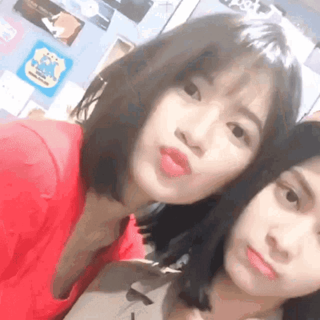 two girls are posing for a picture and one of them is wearing a red top