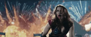a woman in a superhero costume is standing in front of a firework display .
