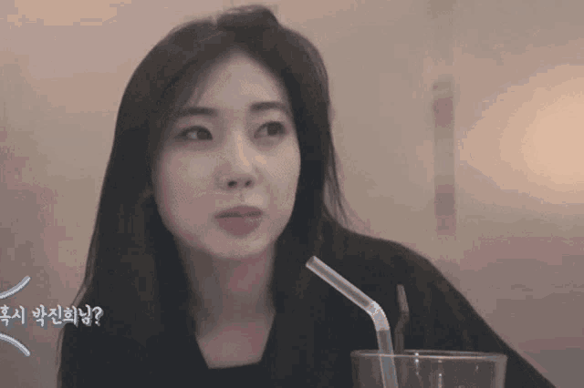 a woman sitting at a table with a glass and a straw