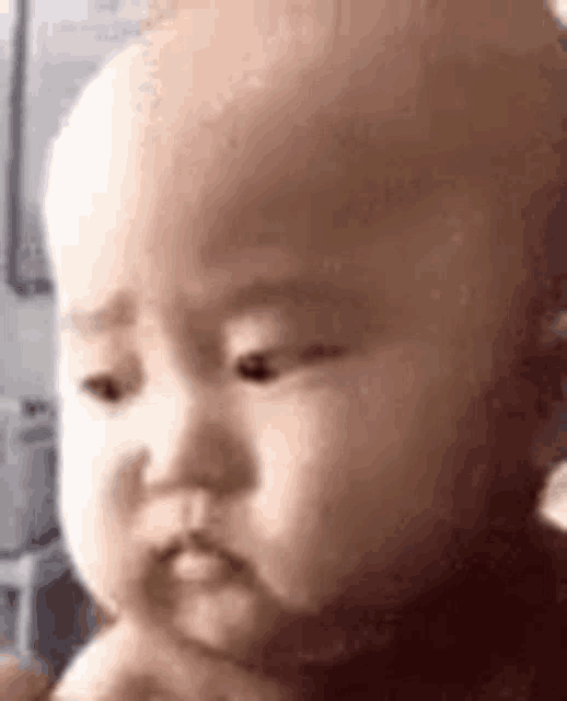 a close up of a baby making a funny face with his hand in his mouth .