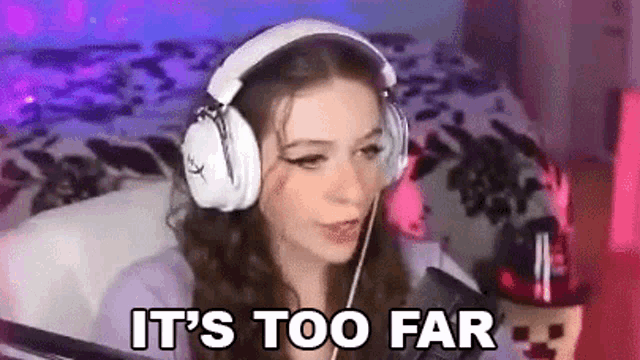 a girl wearing headphones is sitting in front of a microphone and says `` it 's too far '' .