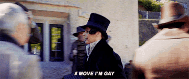 a man in a top hat says move i 'm gay in front of a crowd of people