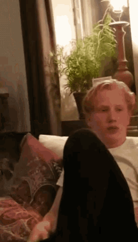 a young man sits on a couch with his feet up