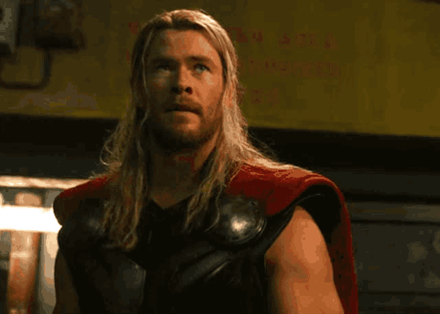 a man with long hair and a beard is wearing a cape and a black vest .