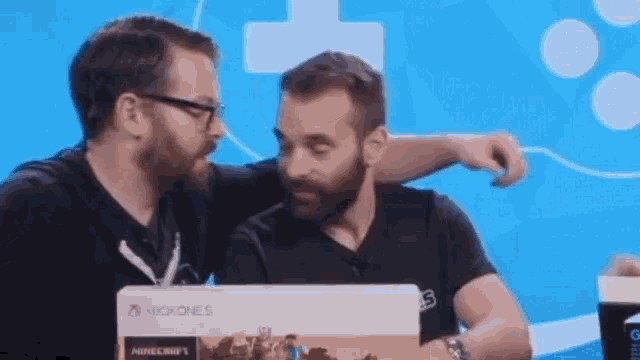two men are looking at a xbox one s box