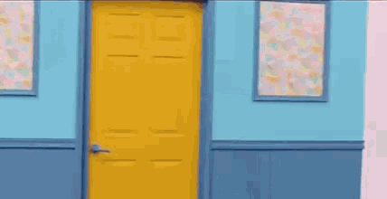 a woman is standing in a doorway holding a yellow door open .