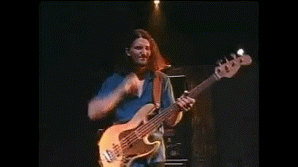 a man in a blue shirt is playing a guitar on stage .