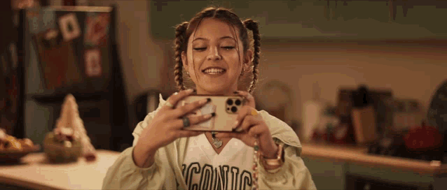 a girl wearing a iconic shirt takes a picture of herself with her phone