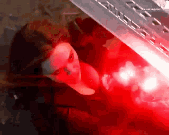 a woman is looking out of a car window with a red light behind her .