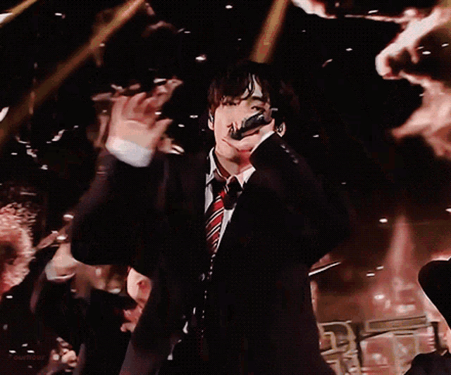 a man in a suit and tie is singing into a microphone on stage