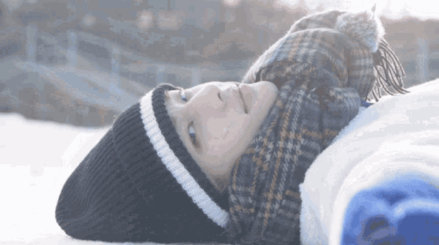 a person wearing a scarf and a hat is laying in the snow