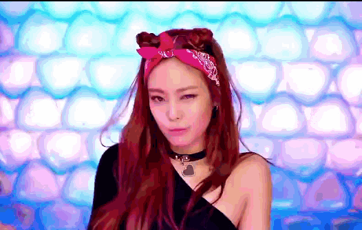 a woman with red hair is wearing a pink headband and a black top .