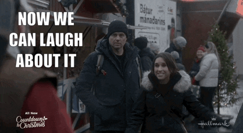 a man and woman are standing in front of a sign that says ' now we can laugh about it '