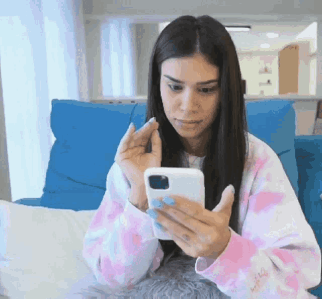 a woman in a pink and white tie dye sweatshirt is looking at her phone