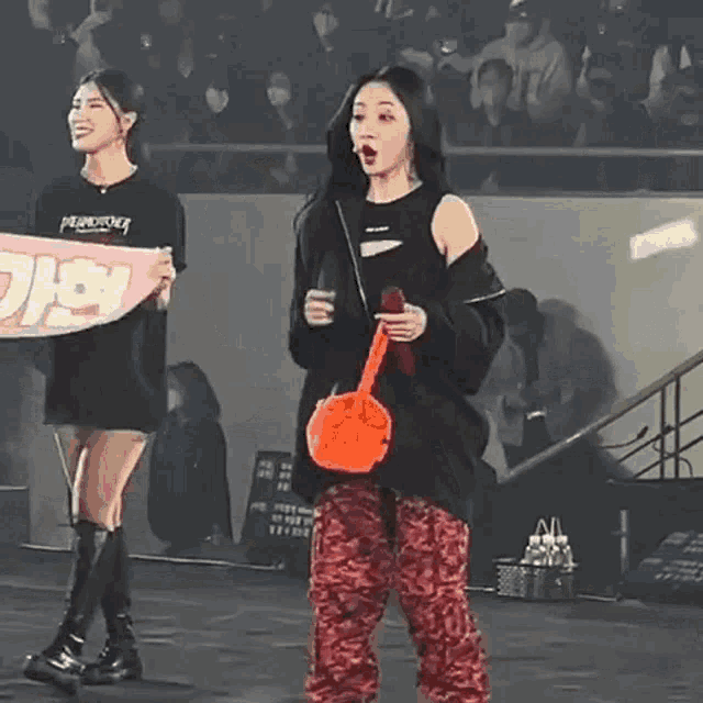 a woman holding a sign that says ' pearlsong ' on it stands next to another woman